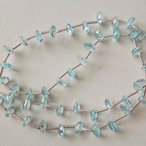 May include: A strand of light blue aquamarine gemstone beads strung on silver wire.