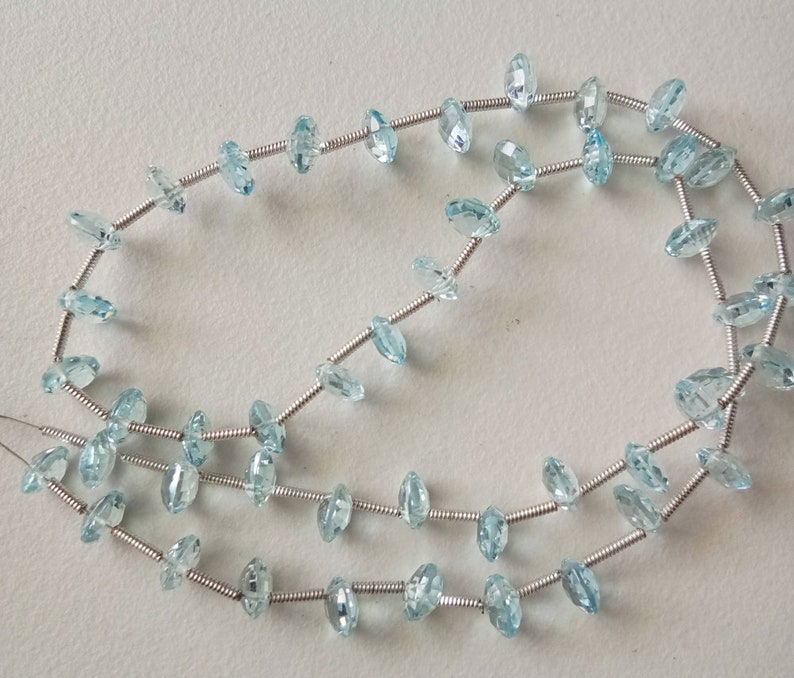 May include: A strand of light blue aquamarine gemstone beads strung on silver wire.