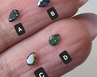 May include: Close-up of four pear-shaped gemstones in shades of blue and green. The gemstones are labeled A, B, C, and D. The gemstones are displayed on a light-colored surface.
