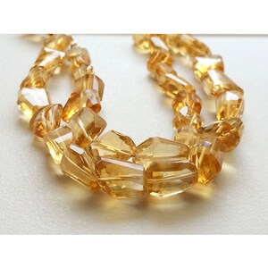 May include: A strand of golden citrine gemstone beads, each bead is faceted and has a rectangular shape.
