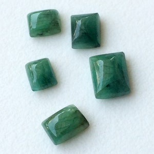 May include: Five emerald green gemstone cabochons in various sizes and shapes. The gemstones are cut into rectangular and square shapes.