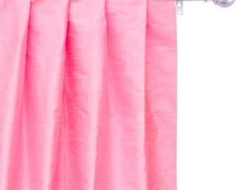 May include: A pink curtain with pleats hangs from a silver curtain rod with a finial.