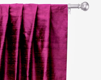 Puede incluir: Un panel de cortina de seda magenta oscuro con un brillo sutil. La cortina está colgada de una barra de cortina plateada con un terminal.