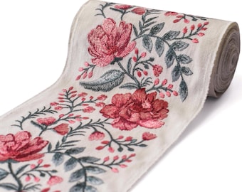 May include: A roll of cream-colored ribbon with an embroidered floral design. The embroidery features large, red peony-like flowers, small pink buds, and green leaves. The ribbon is rolled up, showing the edge of the fabric.