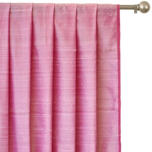 May include: Pink silk curtains with a subtle sheen and a delicate texture. The curtains are hung on a silver rod with a finial.