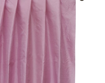 May include: A single pink curtain panel hanging from a black curtain rod with wooden finials.