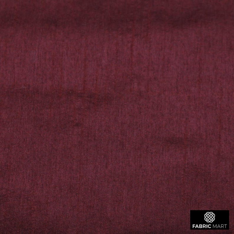 May include: A close-up of a deep burgundy fabric with a subtle texture. The fabric has a smooth, even surface and a rich, dark color.