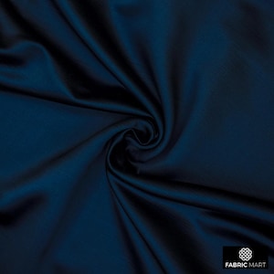 May include: A close-up of a deep blue fabric with a smooth, silky texture. The fabric is folded and draped, showcasing its luxurious feel.