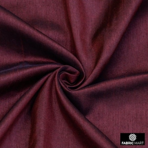 May include: Close-up of a deep burgundy fabric with a subtle sheen. The fabric is smooth and has a slight texture.