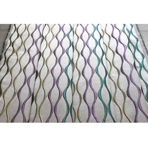 Puede incluir: Tela blanca con un patr&oacute;n repetitivo de l&iacute;neas onduladas en tonos de morado, verde y beige.