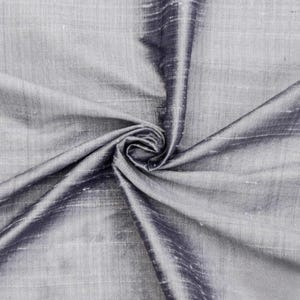 May include: A close-up of a silver and black silk fabric. The fabric is smooth and has a subtle sheen. It is draped and folded to show its texture.