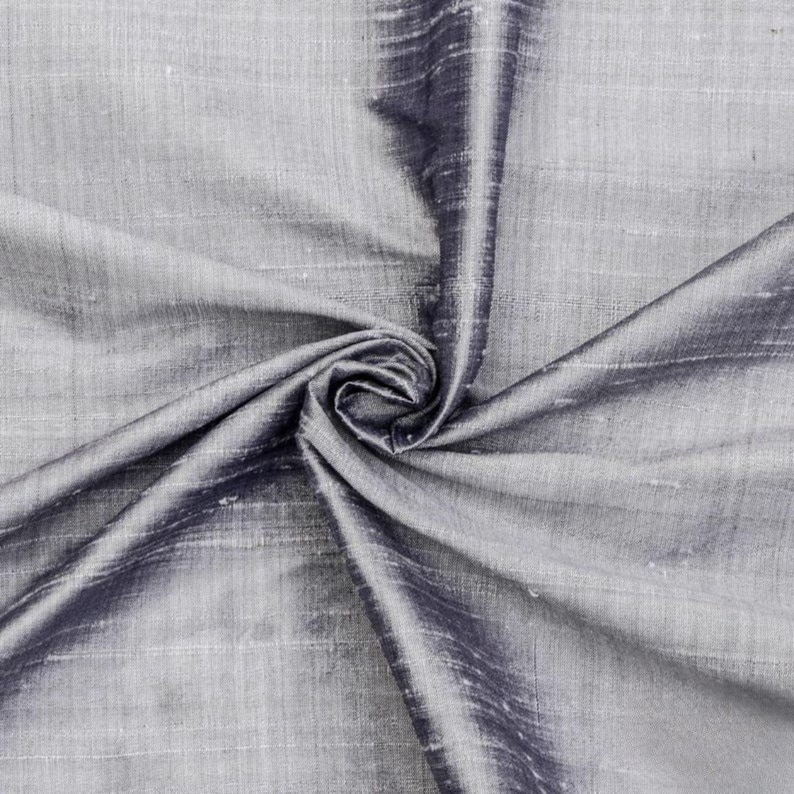May include: A close-up of a silver and black silk fabric. The fabric is smooth and has a subtle sheen. It is draped and folded to show its texture.