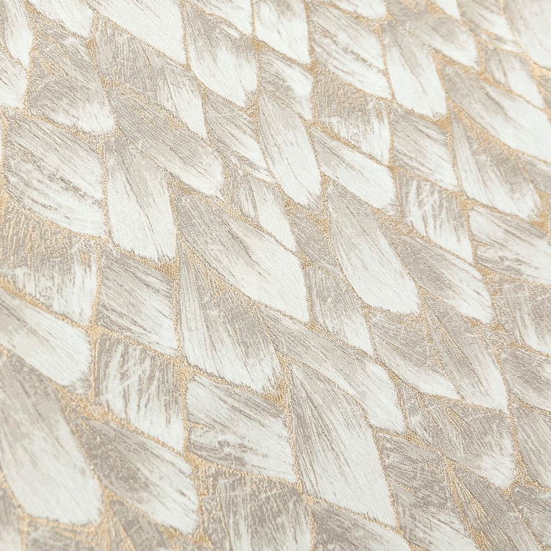 May include: A close-up of a woven fabric with a textured, herringbone pattern. The fabric is a light beige color with a subtle shimmer.