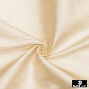 May include: Cream colored silk fabric with a subtle sheen and a smooth texture. The fabric is draped and folded, showcasing its luxurious feel.