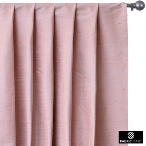 May include: A pair of blush pink curtains with pleats hanging from a curtain rod.