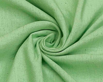 May include: A close-up of a soft, green fabric with a textured surface. The fabric is folded and draped, showing its texture and drape.