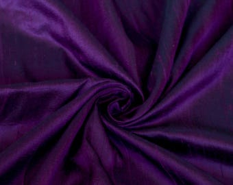 May include: Purple silk fabric with a subtle sheen. The fabric is draped and folded, showcasing its texture and drape.