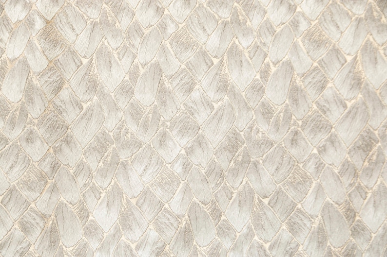 May include: A close-up of a white fabric with a woven pattern that resembles scales. The fabric has a subtle sheen and a slightly textured surface.