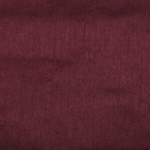 May include: A close-up of a deep burgundy fabric with a subtle texture. The fabric has a smooth, even surface with a slight sheen.