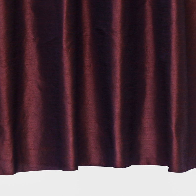 May include: Close-up of a deep burgundy fabric with a silky sheen and subtle folds. The fabric has a smooth, luxurious texture.