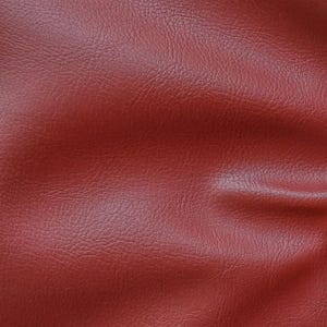 May include: Close-up of a textured, red leather material. The leather has a slightly wrinkled appearance.