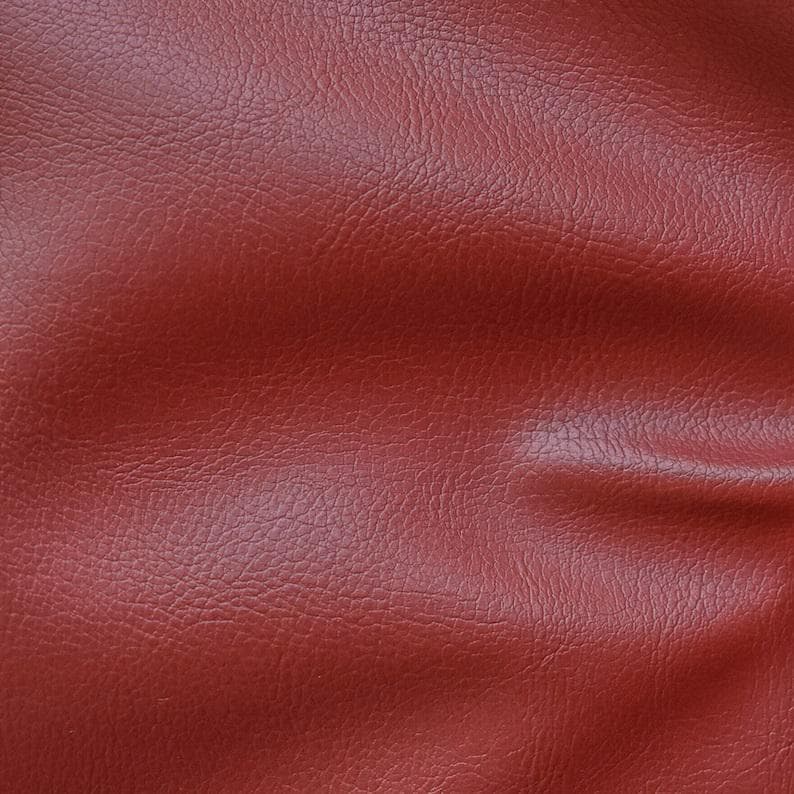 May include: Close-up of a textured, red leather material. The leather has a slightly wrinkled appearance.