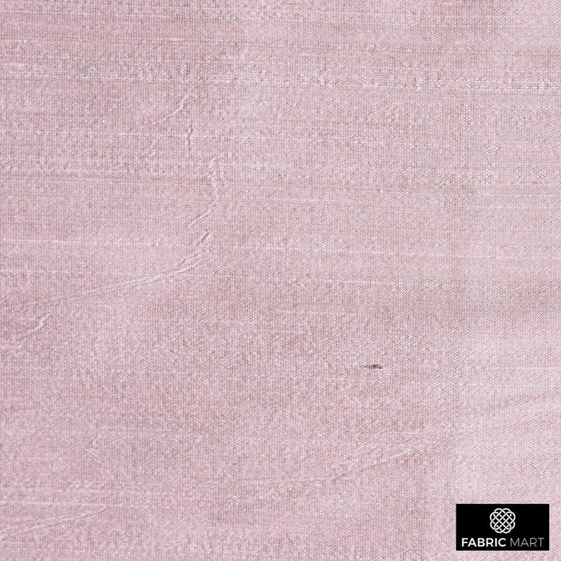 May include: A close-up of a pale pink fabric with a subtle woven texture. The fabric has a smooth, silky feel.