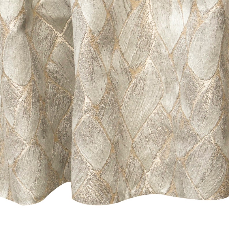 May include: A close-up of a beige and gold fabric with a woven pattern of overlapping leaves.