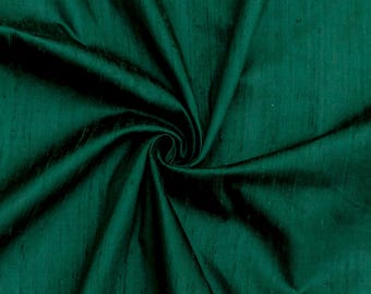 May include: A deep green silk fabric with a smooth, lustrous texture. The fabric is draped and folded, showcasing its soft drape and subtle sheen.