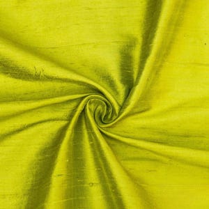 May include: A close-up of a smooth, green fabric with a silky texture. The fabric is folded and draped, showing its soft, flowing nature.