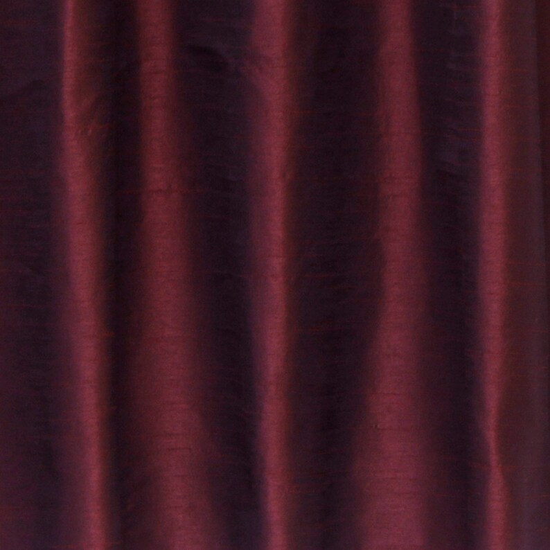 May include: Close-up of a deep burgundy fabric with a subtle sheen. The fabric has a smooth, silky texture and a slightly wrinkled appearance.