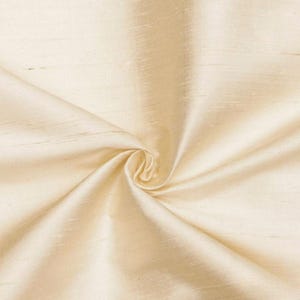May include: Cream colored fabric with a smooth, silky texture. The fabric is folded and draped, showing its soft, flowing nature.
