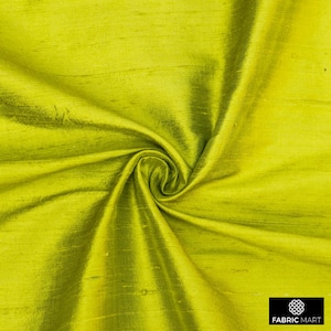 Puede incluir: Primer plano de una tela de seda verde brillante con una textura lisa y brillante. La tela está doblada y drapeada, mostrando su tacto lujoso.