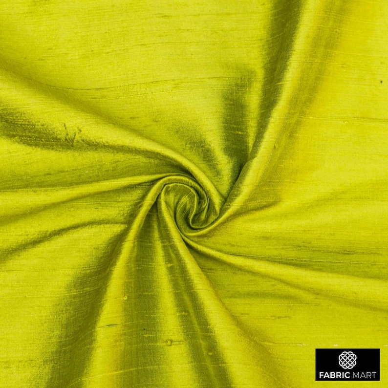 May include: A close-up of a bright green silk fabric with a smooth, shiny texture. The fabric is folded and draped, showcasing its luxurious feel.