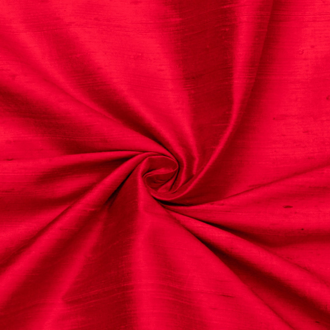 A red silk cloth is draped over a table with soft light on it
