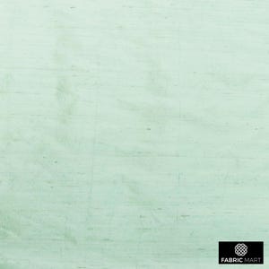 May include: A light green textured fabric with a subtle sheen. The fabric has a woven appearance and a smooth, soft feel.