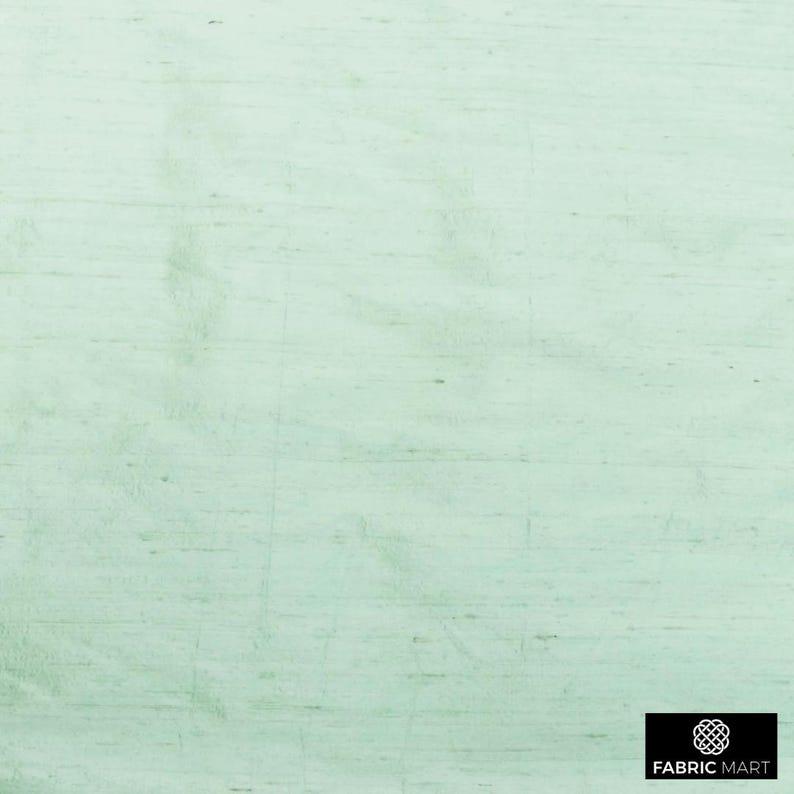 May include: A light green textured fabric with a subtle sheen. The fabric has a woven appearance and a smooth, soft feel.