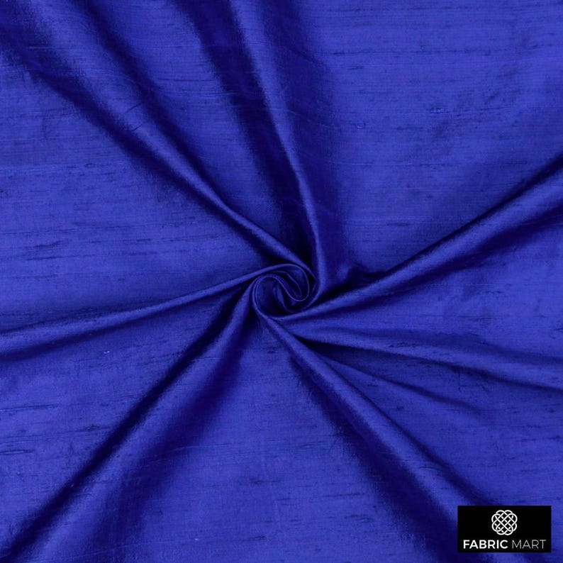 May include: A close-up of a deep blue silk fabric with a subtle sheen. The fabric is folded and draped, showcasing its texture and drape.