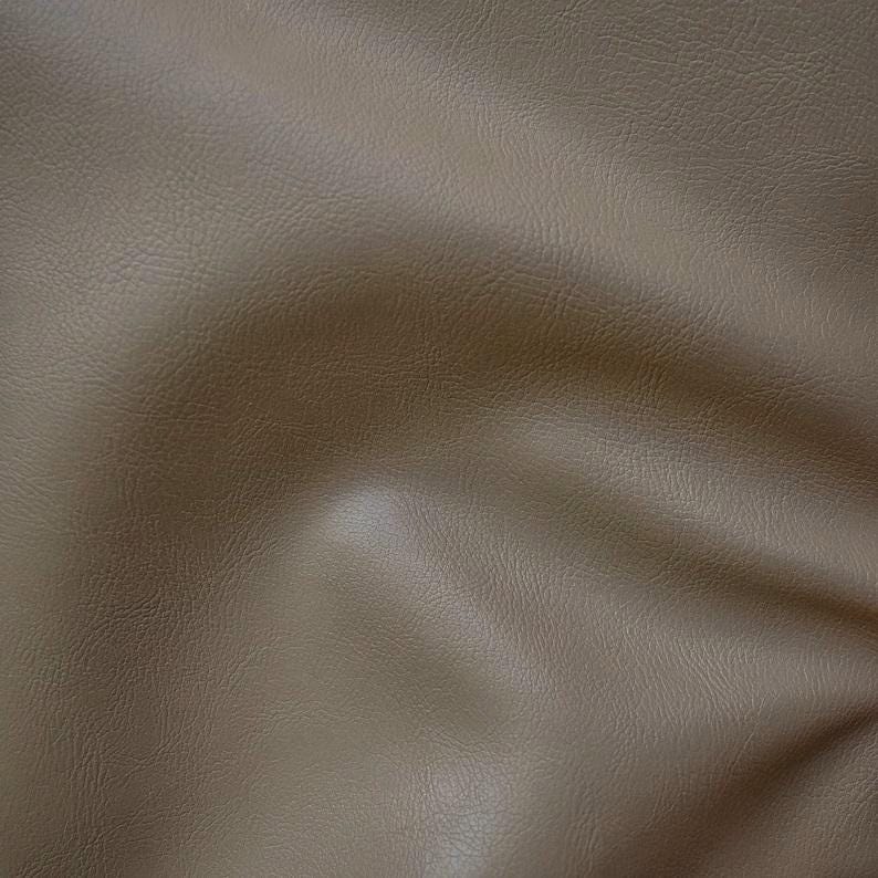 May include: A close-up of a brown faux leather fabric with a textured surface.
