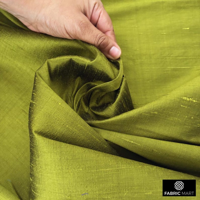 Puede incluir: Primer plano de una tela de seda verde con un brillo sutil. La tela est&aacute; doblada y drapeada, mostrando su textura y ca&iacute;da.