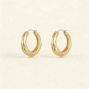May include: A pair of gold-colored hoop earrings. The earrings have a textured, wavy design and a polished finish. The hoops are round and have a classic clasp closure. The earrings are displayed against a neutral background.