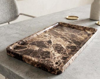 May include: A rectangular serving tray with a marble design. The tray has a brown and beige pattern with a glossy finish. The tray is on a gray surface.