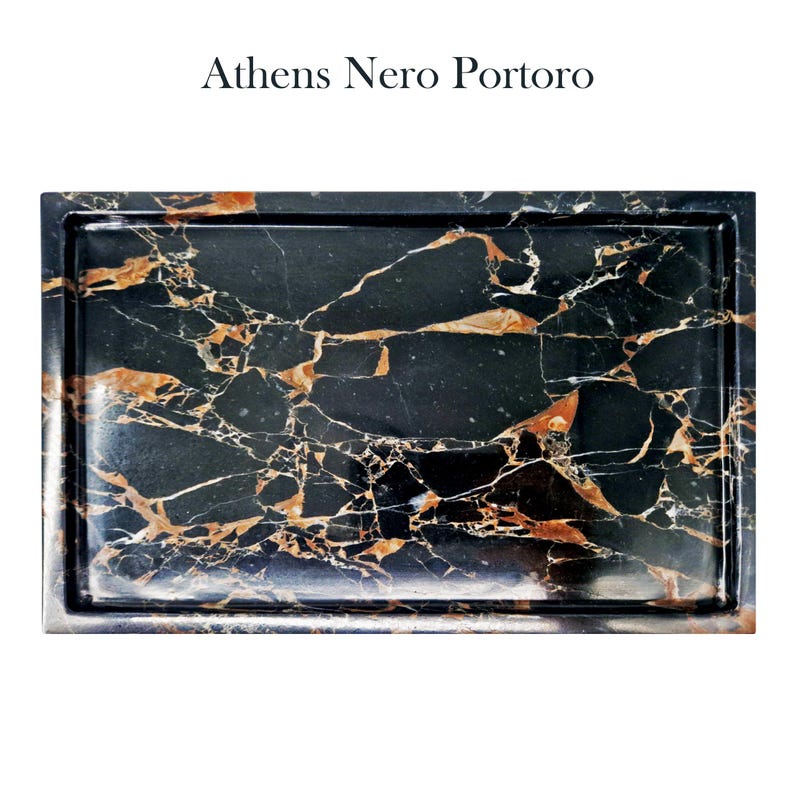 Puede incluir: Bandeja rectangular de m&aacute;rmol negro con vetas doradas y blancas. La bandeja tiene un borde elevado y el texto "Athens Nero Portoro" en la parte superior. El m&aacute;rmol tiene un acabado pulido, mostrando los patrones y colores naturales.
