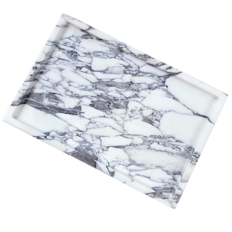 Puede incluir: Bandeja rectangular de m&aacute;rmol con base blanca y vetas grises. La bandeja tiene un borde elevado y un acabado pulido. Esta bandeja decorativa es adecuada para servir o exhibir art&iacute;culos.