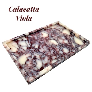 May include: Rectangular tray with a marbled pattern in shades of white, burgundy, and dark purple. The tray has a raised edge and the text "Calacatta Viola" in a dark brown font.