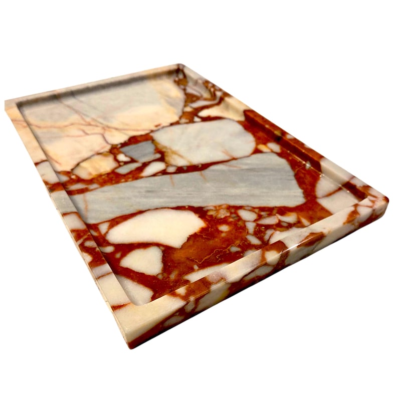 May include: A rectangular marble tray with a raised edge. The tray features a pattern of red, white, and gray veining. The tray is made of stone and is suitable for serving or display.