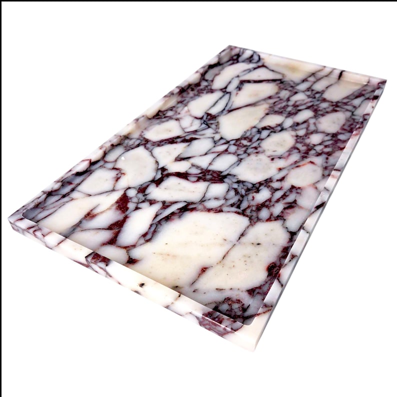 May include: Rectangular tray with a marble design. The tray has a white base with burgundy and dark grey veining. The edges are smooth and polished. This tray is suitable for serving or display. Dimensions are approximately 30 cm x 15 cm.