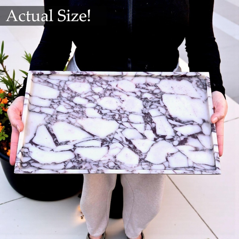 May include: Rectangular serving tray with a white and purple marble design. The tray has a raised edge and the text "Actual Size!" in the upper left corner. The tray is being held by a person.