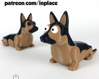May include: Two 3D-printed German Shepherd dog figurines. The dogs are tan and black, with large, cartoonish eyes. The text "patreon.com/inplace" is at the top, and "INPLACE" is at the bottom.