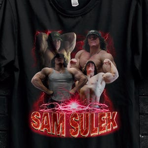 May include: Black t-shirt with a graphic of bodybuilders and the text "SAM SULEK" in red. The shirt displays the "STITCH AURA" logo and a promotional offer for bulk purchases.
